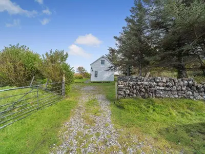 a white house with a fence and a field at The Stables - Uk37415 in Bunessan