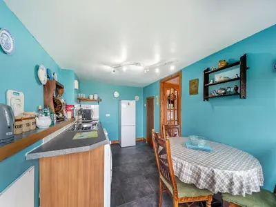 a kitchen with blue walls and a table and a table and chairs at The Stables - Uk37415 in Bunessan