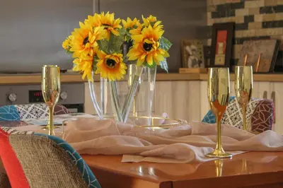 a table with yellow flowers and wine glasses on it at Deluxe Apartment in Lanark
