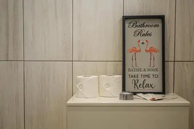 a sign on top of a toilet tank with toilet paper at Deluxe Apartment in Lanark