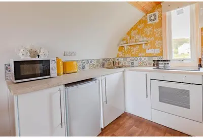 a kitchen with white cabinets and a microwave at The Galloway Steading- The Bee Hive Couples Retreat with Hot Tub and Fire Pit in Glenluce