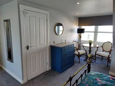 a bedroom with a blue dresser and a table at Fabulous 2BD Maisonette Dunfermline, Fife in Dunfermline