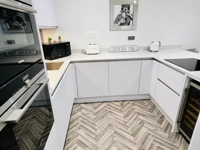 a kitchen with white cabinets and a wooden floor at DESIGNER HOUSE - University of Glasgow / Central Glasgow 'Hillhead' West End G12 - Luxurious & Contemporary Detached House / Terrace / Garden / 'electric car charging' Garage Parking in Glasgow