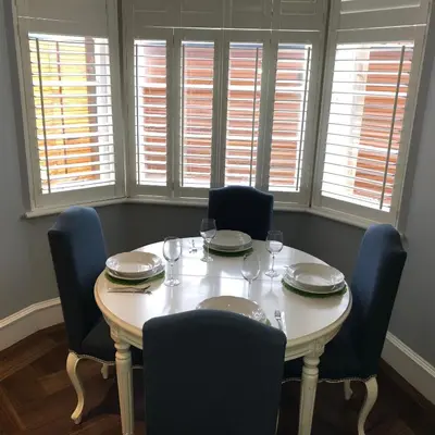 a dining room table with chairs and plates and windows at Stylish 2 Bedroom Apartment In Park Circus, West End in Glasgow