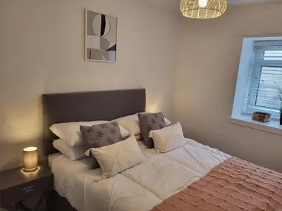 a bedroom with a bed with pillows and a window at The Bailey - Troon - Coorie Doon Stays in Troon