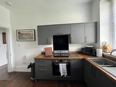 a kitchen with gray cabinets and a stove top oven at The Lowry .. Where elegance meets Luxury! in Oban