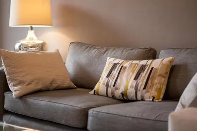 a couch with two pillows sitting next to a lamp at Exclusive 2 Bed, Free Private Parking, in West End in Edinburgh
