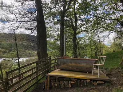 a bench sitting next to a fence with a view of a river at The Loveshack Lodge Balquhidder in Balquhidder