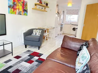 a living room with a brown leather couch and a kitchen at Bright 2 Bedroom Apartment - Edinburgh in Edinburgh