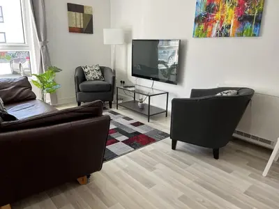 a living room with two couches and a flat screen tv at Bright 2 Bedroom Apartment - Edinburgh in Edinburgh