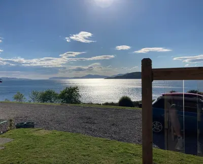 a car parked next to a fence with a view of the water at Craigneuk near Oban, stunning home with sea views in Oban