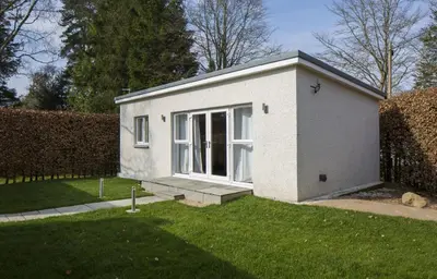 a small white house with a window in a yard at White Cottage - Cosy Holiday Cottage in Drymen, Loch Lomond & Trossachs in Drymen
