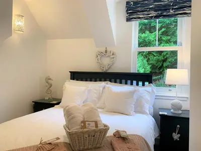 a bedroom with a bed with white pillows and a window at Coorie Doon in Cairnbaan