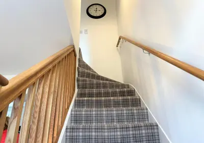 a staircase with a stair case and a clock on the wall at Coorie Doon in Cairnbaan