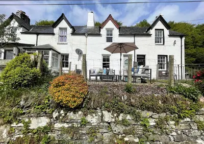 a white house with an umbrella in front of it at Coorie Doon in Cairnbaan