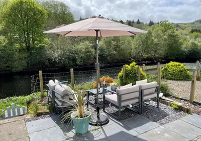a patio with an umbrella and two chairs and a table at Coorie Doon in Cairnbaan