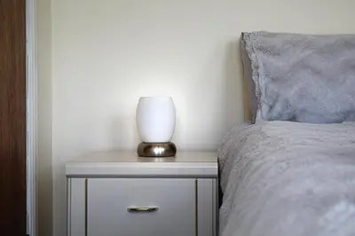 a lamp on a night stand next to a bed at Tinto View Apartment in Carstairs