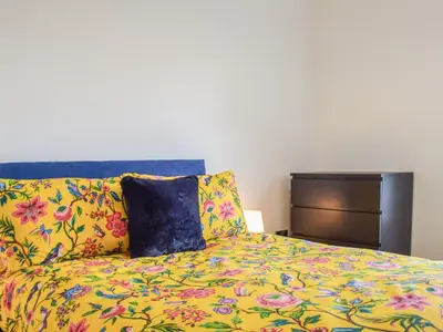 a bed with a colorful comforter and two pillows at The Wee White Cottage in Bannockburn