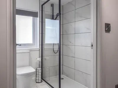 a bathroom with a glass shower with a toilet at The Wee White Cottage in Bannockburn