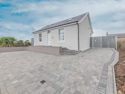 a white house with a fence and a patio at The Wee White Cottage in Bannockburn