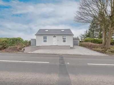 a white house sitting on the side of a road at The Wee White Cottage in Bannockburn