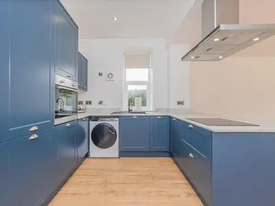 a kitchen with blue cabinets and a washing machine at The Wee White Cottage in Bannockburn