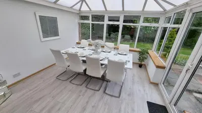 a dining room with a table and white chairs at Rozelle Villa in Ayr