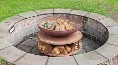 a fire pit with a bowl on a pile of wood at Stylish Loch Lomond lodge in stunning surroundings in Balloch