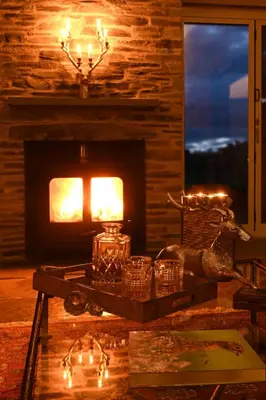 a room with a fireplace and a table with christmas lights at Laverockbank Steading in Buchanty