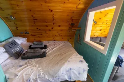 a bed in a room with a wooden wall at Fulshaw Mill Holidays in Stewarton