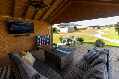 a patio with a couch and a tv and a table at Fulshaw Mill Holidays in Stewarton