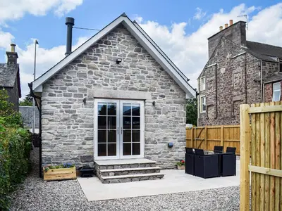 a small stone house with a wooden fence at Rubys Cottage in Crieff