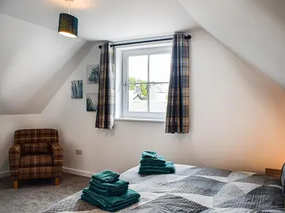 a bedroom with a bed and a window at Rubys Cottage in Crieff