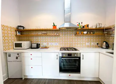 a kitchen with white cabinets and a stove top oven at Open Plan 2 Bed Apt, Near Edinburgh Castle in Edinburgh