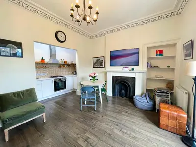a living room with a table and a fireplace at Open Plan 2 Bed Apt, Near Edinburgh Castle in Edinburgh