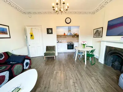 a living room with a table and a fireplace at Open Plan 2 Bed Apt, Near Edinburgh Castle in Edinburgh