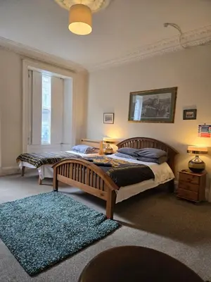 a bedroom with two beds and a blue rug at The Braveheart House in Edinburgh