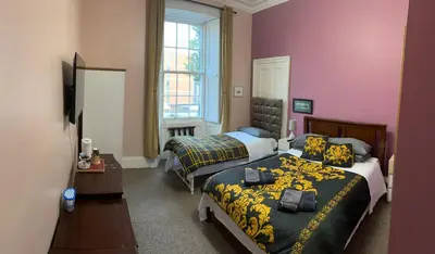 two beds in a room with purple walls at The Braveheart House in Edinburgh