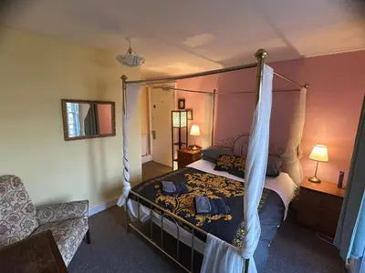 a bedroom with a canopy bed and a chair at The Braveheart House in Edinburgh