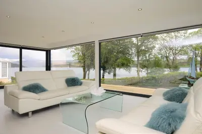 a living room with two white couches and a glass table at The Lookout in Tighnabruaich
