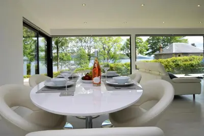 a white dining room with a white table and chairs at The Lookout in Tighnabruaich