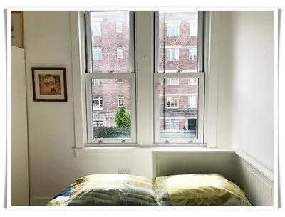 a bedroom with two windows and a bed in front at Spacious and modern 2 bedroom flat near the City Centre in Edinburgh