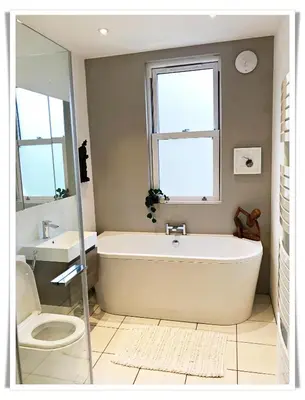 a bathroom with a tub and a toilet and a window at Spacious and modern 2 bedroom flat near the City Centre in Edinburgh