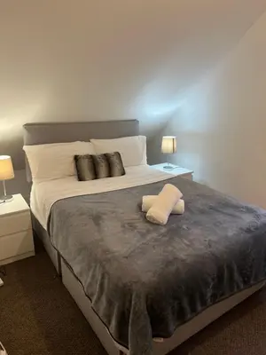 a bedroom with a large bed with two lamps at 4 bed bungalow near Airport in Edinburgh