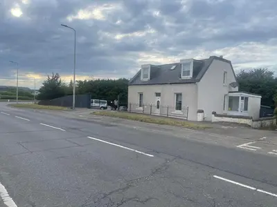a white house sitting on the side of a road at 4 bed bungalow near Airport in Edinburgh