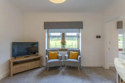 a living room with two chairs and a television at Wilsons Cottage in Falkirk