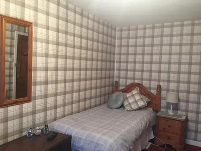 a small bedroom with a bed and a mirror at Rooms at Tarrareoch in Bathgate