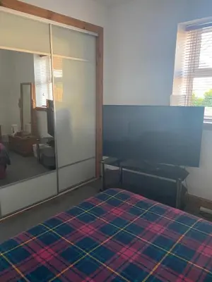 a room with a bed and a sliding glass door at Rooms at Tarrareoch in Bathgate