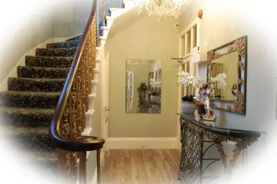 a hallway with stairs and a chandelier at Highlander House Boutique Hotel in Rothesay