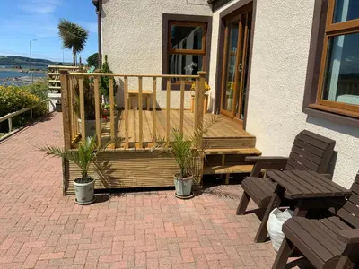 a patio with two chairs and a wooden deck at Cairnryan Bed and Breakfast in Cairnryan